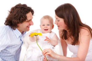 un papa et une maman montrent une fleur à leur bébé