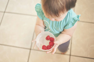 Un bébé en âge de marcher se régale avec un bol de framboises
